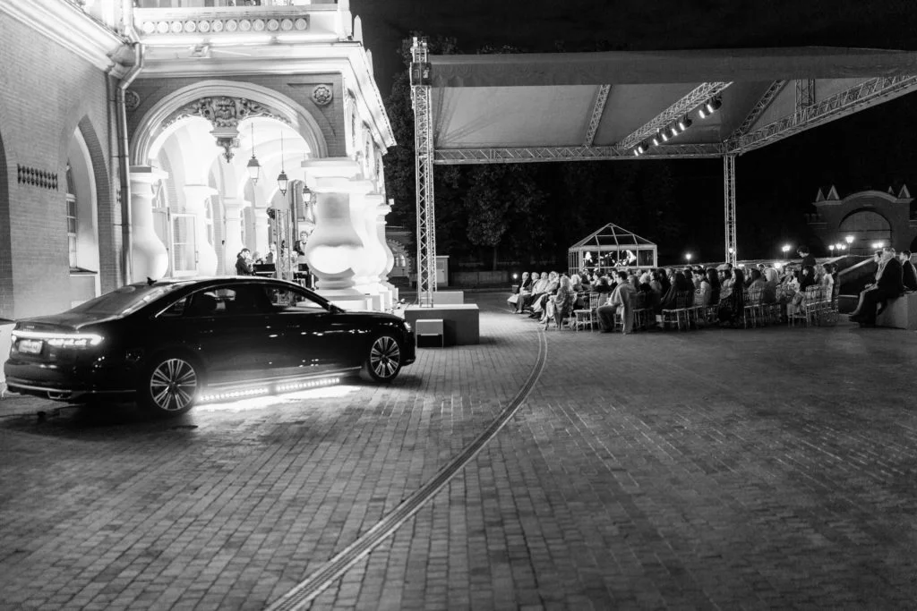 Автомобиль Audi и вечерняя концертная площадка