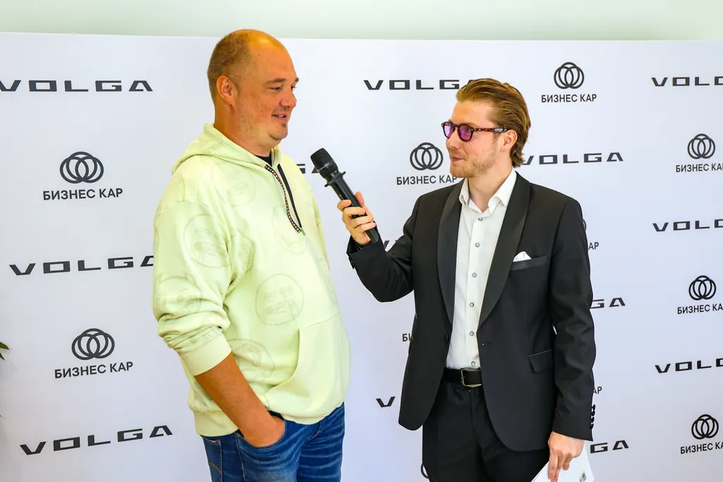 Ведущий общается с гостем на фоне бренда VOLGA